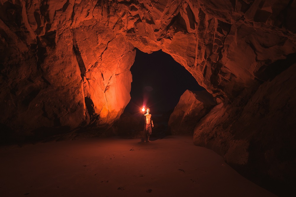 A man with a torch explores a cave.